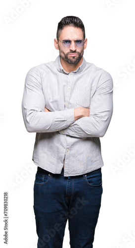 Young handsome man wearing sunglasses over isolated background skeptic and nervous, disapproving expression on face with crossed arms. Negative person.