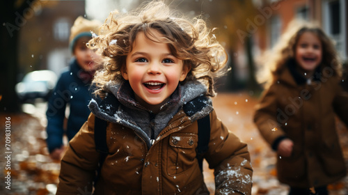 Little kids of elementary class walking to school during snowfall. Happy children having fun and playing with first snow.