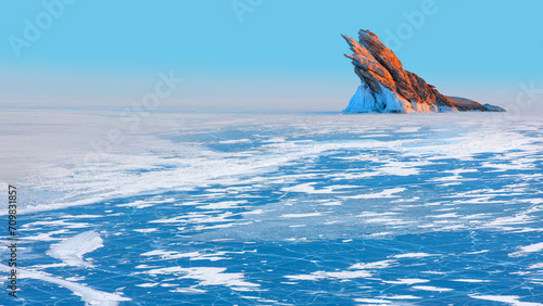 Beautiful winter landscape of frozen Lake Baikal at sunrise - A granite rock with steep slopes rises above a frozen lake - Baikal lake, Siberia © muratart