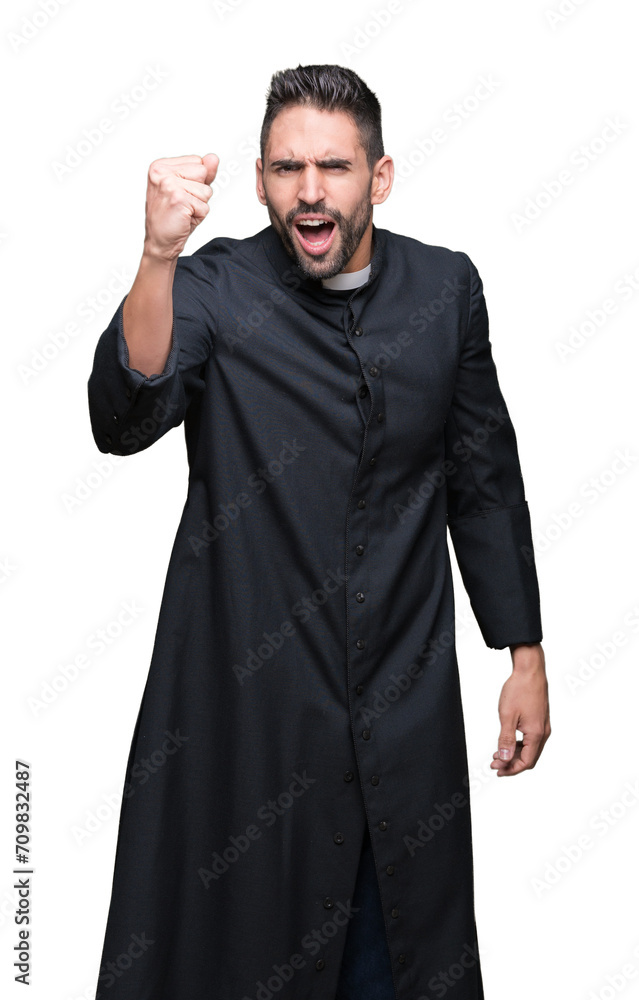 Young Christian priest over isolated background angry and mad raising fist frustrated and furious while shouting with anger. Rage and aggressive concept.