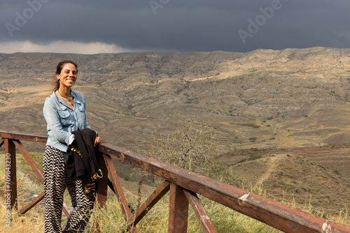 portrait of woman smiling at kakheti steppe landscape with dry neadow and sandstone mountains in the background on a sunny day