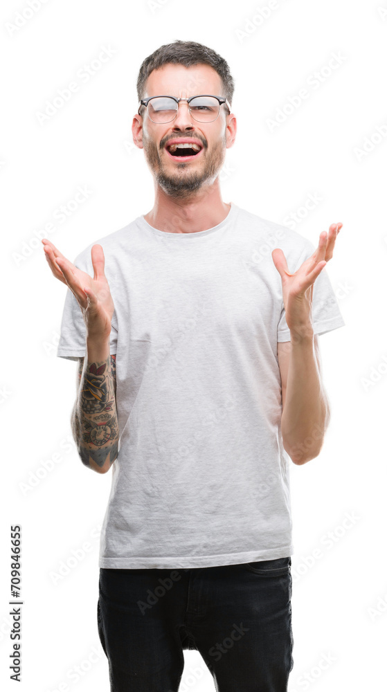 Young tattooed adult man crazy and mad shouting and yelling with aggressive expression and arms raised. Frustration concept. Young tattooed adult man crazy and mad shouting and yelling with aggressive expression and arms raised. Frustration concept.
