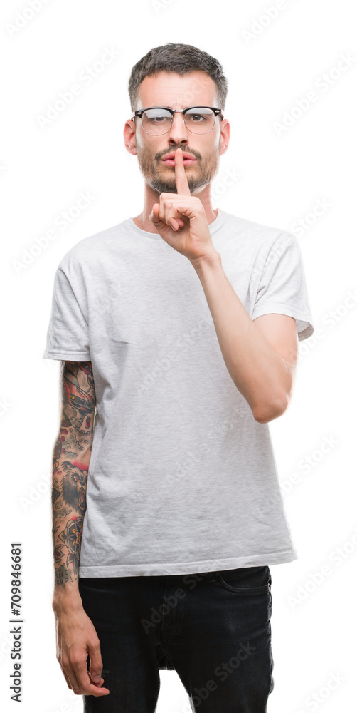 Young tattooed adult man asking to be quiet with finger on lips. Silence and secret concept. Young tattooed adult man asking to be quiet with finger on lips. Silence and secret concept.