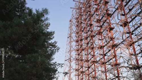 Wallpaper Mural Zoom out Duga radar system view through trees with blue sky on the background in Chernobyl, Ukraine. High quality 4k footage Torontodigital.ca