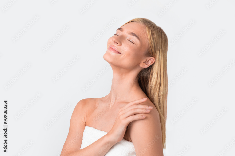Portrait of blonde lady wrapped in towel touching shoulder, studio Portrait of blonde lady wrapped in towel touching shoulder, studio