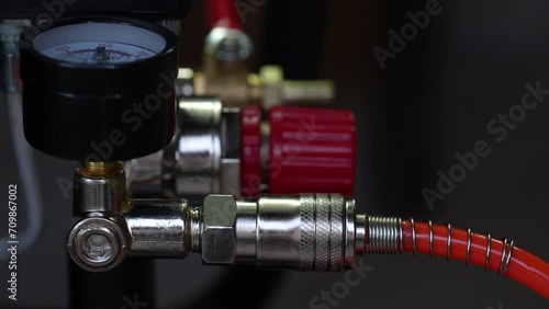Worker connects orange air hose to air compressor via hose coupling, closeup. Spiral hose for supplying air pressure to the instrument and possibility of working at large distance from the main base photo