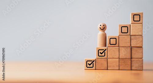 Wooden professional management figure smile and standing on second step of stair with tick checkmark for work task and project planing progressive concept. photo