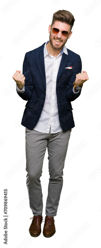 Young handsome elegant man wearing sunglasses and fashion blazer very happy and excited doing winner gesture with arms raised, smiling and screaming for success. Celebration concept. Young handsome elegant man wearing sunglasses and fashion blazer very happy and excited doing winner gesture with arms raised, smiling and screaming for success. Celebration concept.
