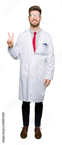 Young handsome scientist man wearing glasses showing and pointing up with fingers number two while smiling confident and happy.