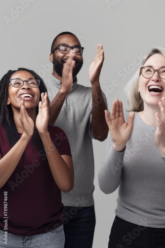 studio shot of a group of people clapping against a gray background