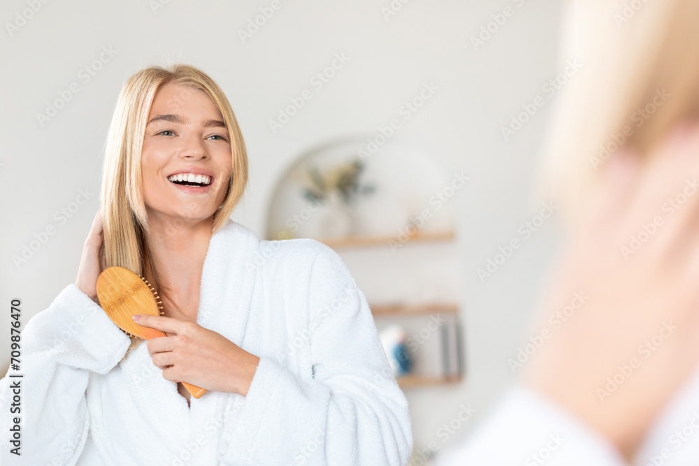blonde lady brushing strong long hair at her home bathroom blonde lady brushing strong long hair at her home bathroom