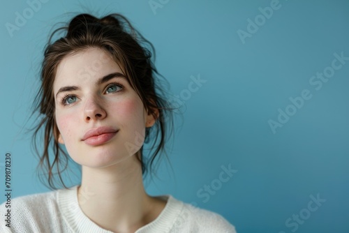 Serene studio portrait of a European woman with a contemplative look, isolated on a blue background