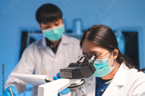 Scientists using microscope to recording ecological  examining and sample of experiment in night laboratory  genetic and chemistry research  discovery of new medicine  develop and analyzing futuristic