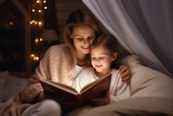 Mom reads a book to her little child, sitting on the sofa and covered with a blanket, lamp light