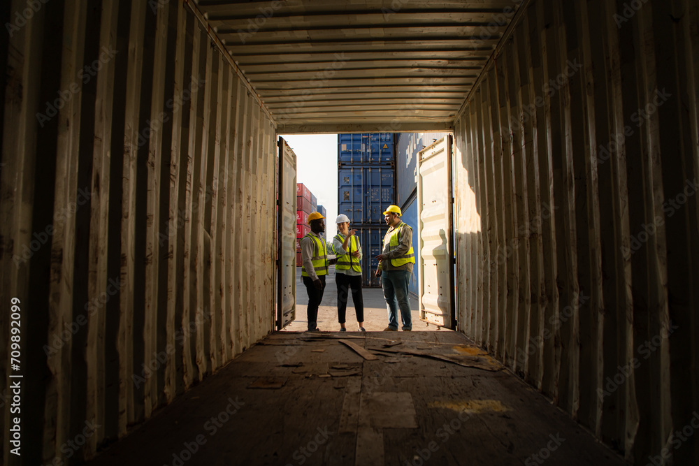 Group of workers in an empty container storage yard, The condition of the old container is being assessed to determine whether it requires maintenance for usage.
