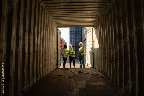 Group of workers in an empty container storage yard  The condition of the old container is being assessed to determine whether it requires maintenance for usage.