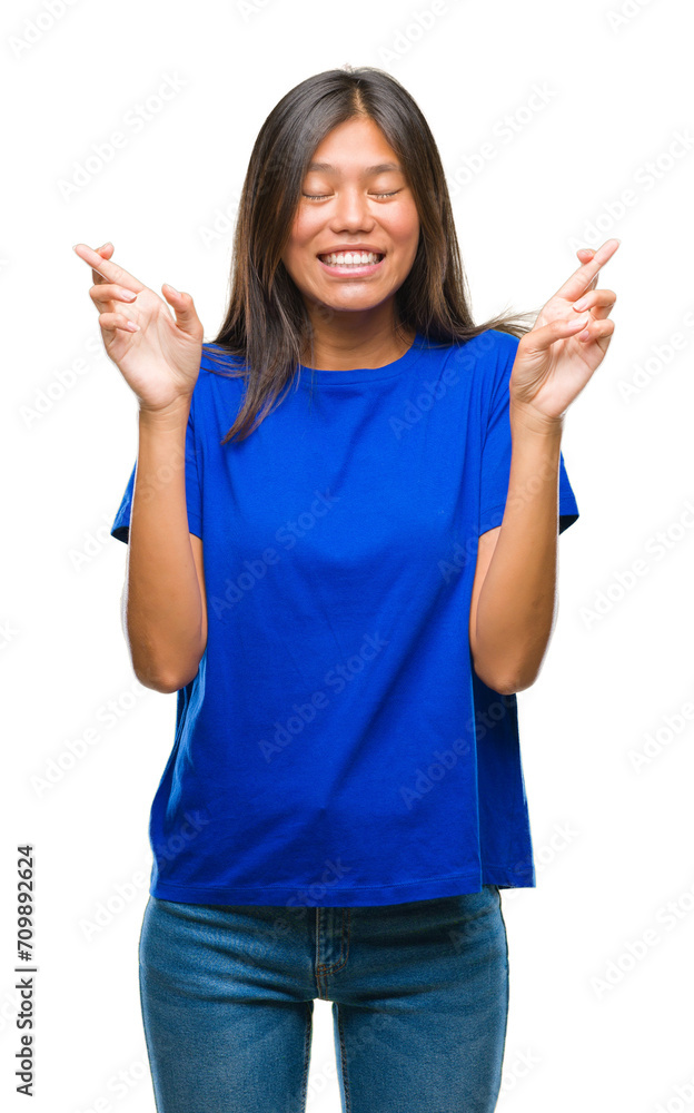 Young asian woman over isolated background smiling crossing fingers with hope and eyes closed. Luck and superstitious concept. Young asian woman over isolated background smiling crossing fingers with hope and eyes closed. Luck and superstitious concept.