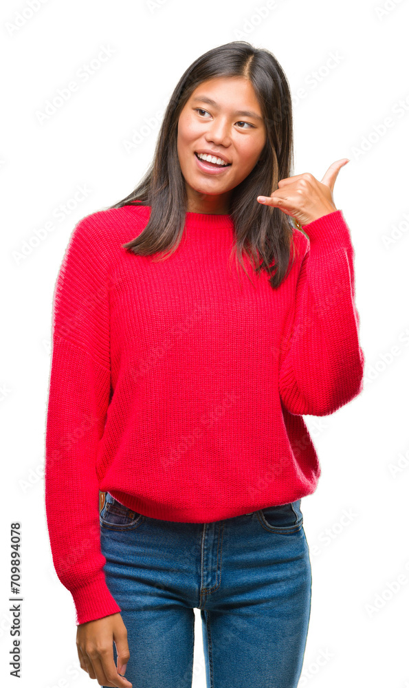 Young asian woman wearing winter sweater over isolated background smiling doing phone gesture with hand and fingers like talking on the telephone. Communicating concepts. Young asian woman wearing winter sweater over isolated background smiling doing phone gesture with hand and fingers like talking on the telephone. Communicating concepts.