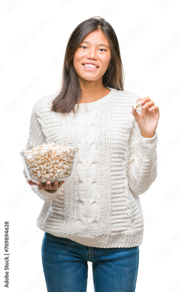 Young asian woman eating popcorn over isolated background with a happy face standing and smiling with a confident smile showing teeth Young asian woman eating popcorn over isolated background with a happy face standing and smiling with a confident smile showing teeth