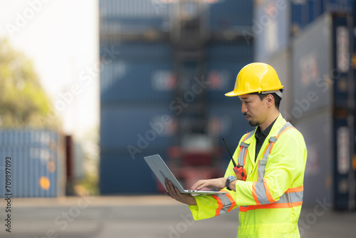 Workers in the import and export industry holding a laptop and standing on the front of container to inspect the container's cargo. photo
