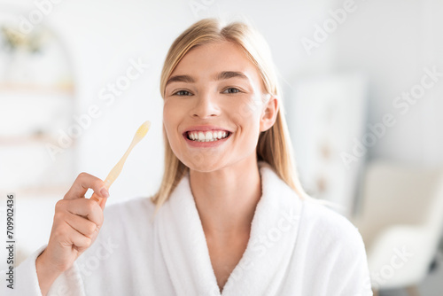 European blonde woman maintaining oral health brushing teeth in bathroom