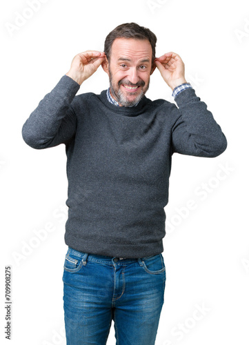 Handsome middle age senior man wearing a sweater over isolated background Smiling pulling ears with fingers, funny gesture. Audition problem