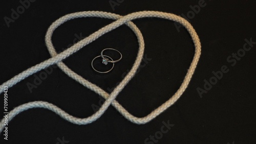 Canvas Print Tying the knot: heart shaped rope, one plain silvery ring and one diamond ring,