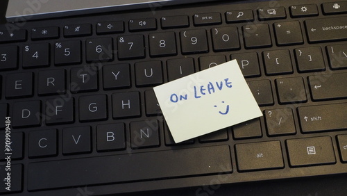yellow sticky note with handwritten words "On Leave" and a smiley, placed on keyboard