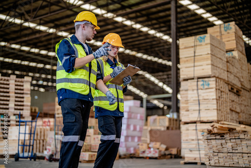 workers man and woman engineering walking and inspecting timbers wood in warehouse. Concept of smart industry worker operating. Wood factories produce wood palate.