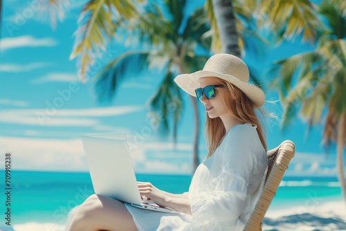 Beautiful young woman  in white dress Working on laptop on the beach, freelance work. © Tar