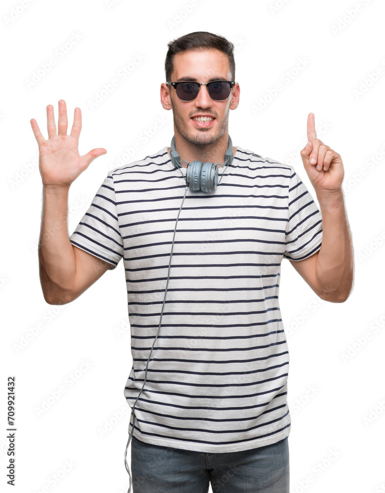 Handsome young man wearing headphones showing and pointing up with fingers number six while smiling confident and happy. Handsome young man wearing headphones showing and pointing up with fingers number six while smiling confident and happy.