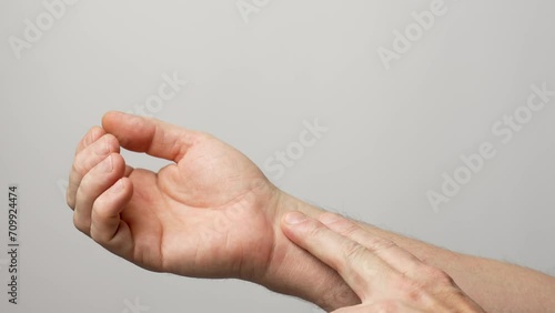 Man checking pulse with fingers on his wrist, close-up photo