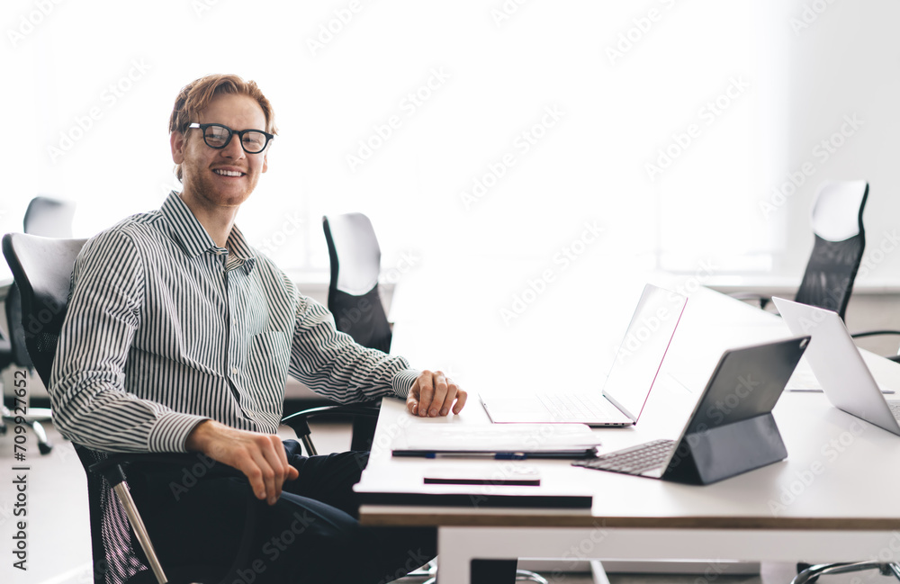 Cheerful businessman sitting with laptops in office Cheerful businessman sitting with laptops in office