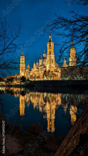 Basilica's Twilight Dance: Moonlit Zaragoza showcases the Pilar, Stone Bridge, and Ebro River in an exquisite nocturnal ballet.
