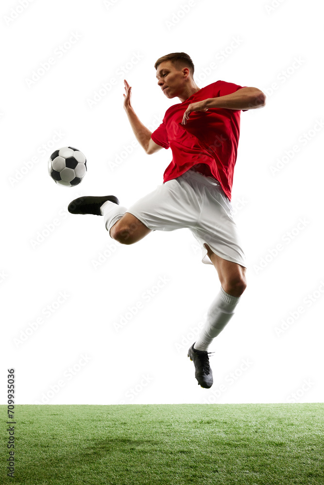 Airborne Brilliance. Dynamic portrait of professional football player as ball defies gravity in flawless mid-air pass against white background. Concept of sport games, hobby, energy, world cup season.