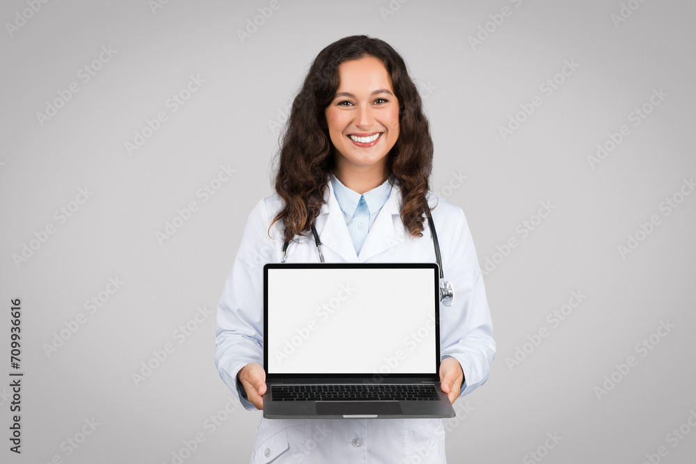 Happy woman doctor showing laptop with empty screen advertising online medical offer or service, mockup Happy woman doctor showing laptop with empty screen advertising online medical offer or service, mockup