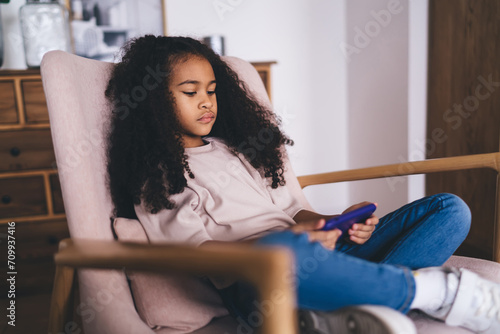 Pensive black girl watching video on smartphone