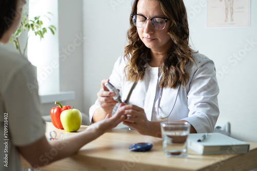 The doctor shows the patient how to use a glucometer. A female endocrinologist is seeing a patient in her office on the topic of measuring blood sugar levels. photo