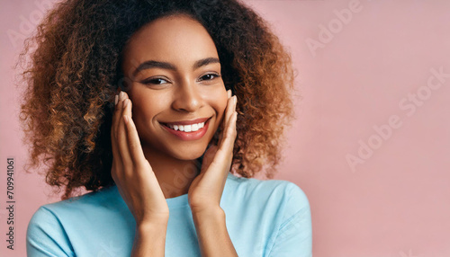 Skincare and Beauty Portrait. Woman with beautiful face touching healthy facial skin. Young adult smiling girl model with natural makeup on pink background closeup. High-quality beauty product