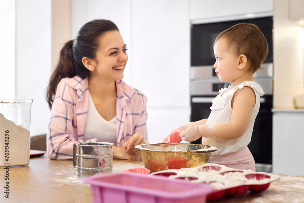 mother and little baby girl preparing the dough in the kitchen, bake cookies. happy time together mother and little baby girl preparing the dough in the kitchen, bake cookies. happy time together