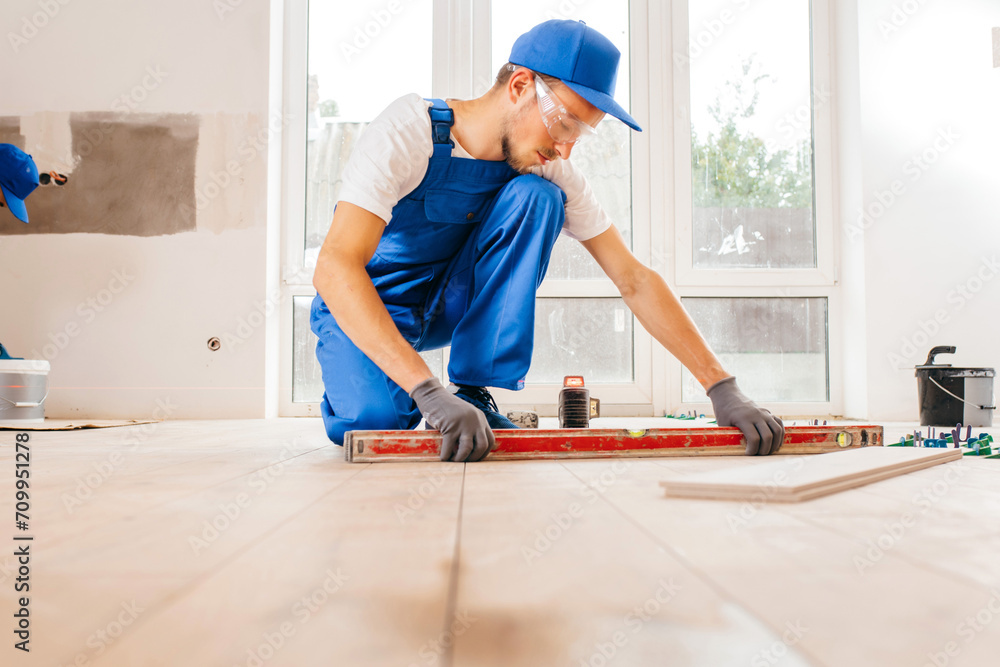 Close up hands of repairman in grey gloves and special uniform laying tiles with tile leveling system on the floor in a new house
Close up hands of repairman in grey gloves and special uniform laying tiles with tile leveling system on the floor in a new house