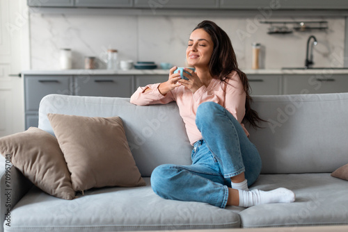 Content woman savoring coffee on comfortable couch photo
