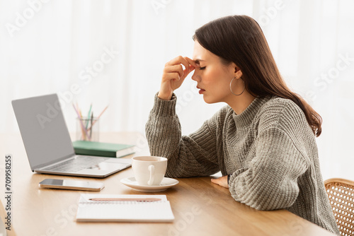 Exhausted young woman entrepreneur sitting at home office photo