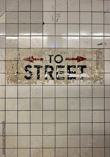 Weathered to street subway sign with arrows left and right on the wall in the subway