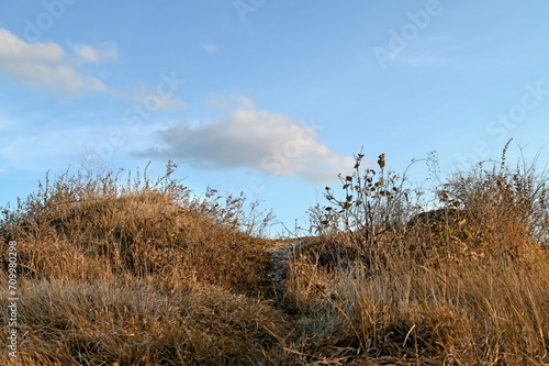 A cloud over a grassy slope in autumn. The path to sky.