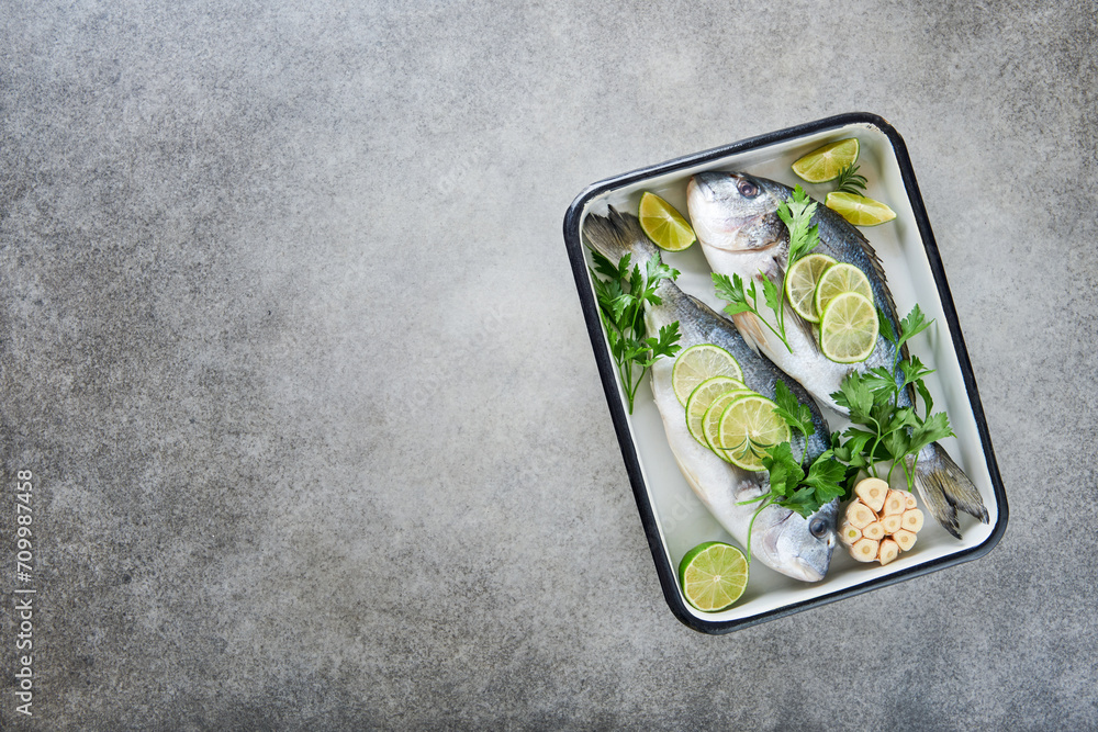 Raw fresh. Fresh raw dorado with lemon, lime, parsley and salt on old grey concrete background ready for cooking. Sea bream, dorado. Seafood, healthy food. Top view. Long banner format. Raw fresh. Fresh raw dorado with lemon, lime, parsley and salt on old grey concrete background ready for cooking. Sea bream, dorado. Seafood, healthy food. Top view. Long banner format.