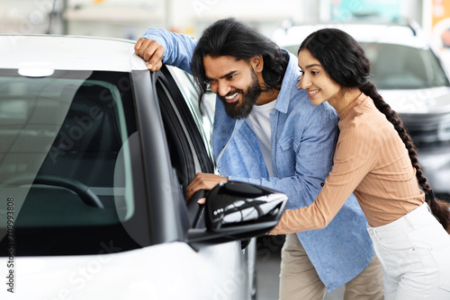 Happy Indian Spouses Looking Inside Of Their New Car Together