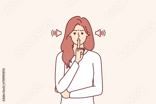 Frowning woman makes tss gesture calling for phones to be turned off or to speak more quietly. Girl orders silence, showing tss sign with hand, to calm down hyperactive children making lot of noise.