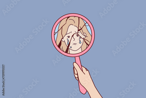 Broken mirror in hand of crying woman and reflection of face of emotionally unstable person in need of antidepressants. Crying girl suffers from bullying or shaming and violation of women rights