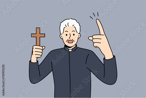 Angry priest with wooden christian cross in hand shouts, urging people to think about approaching day of judgment. Man priest with symbol of catholic church swears to drive out evil spirit